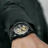 Reloj negro con mecanismo en dorado.