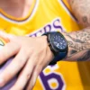 Jugador de baloncesto con el brazo tatuada llevando un reloj azul con detalles negro cromo.